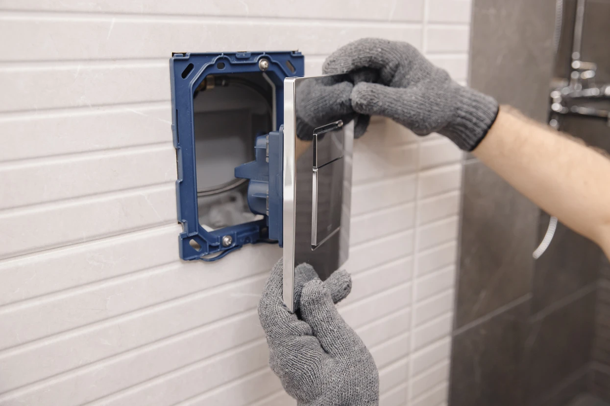 Intérieur salle de bains, personne portant gants de protection gris installant un interrupteur électrique mural