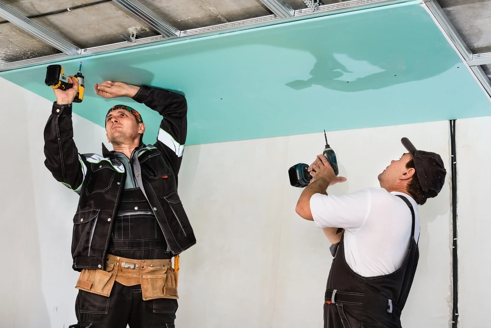 Les ouvriers assemblent un plafond suspendu avec un mur sec