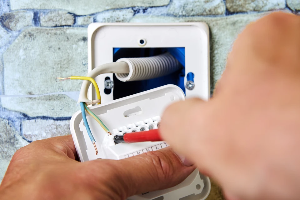 Électricien, électricien installant une nouvelle prise courante avec tournevis