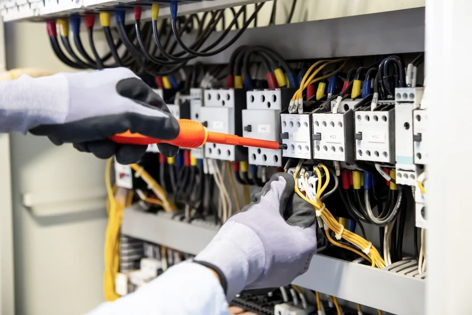 Électricien effectuant des mesures électriques dans un boîtier mural avec multimètre numérique