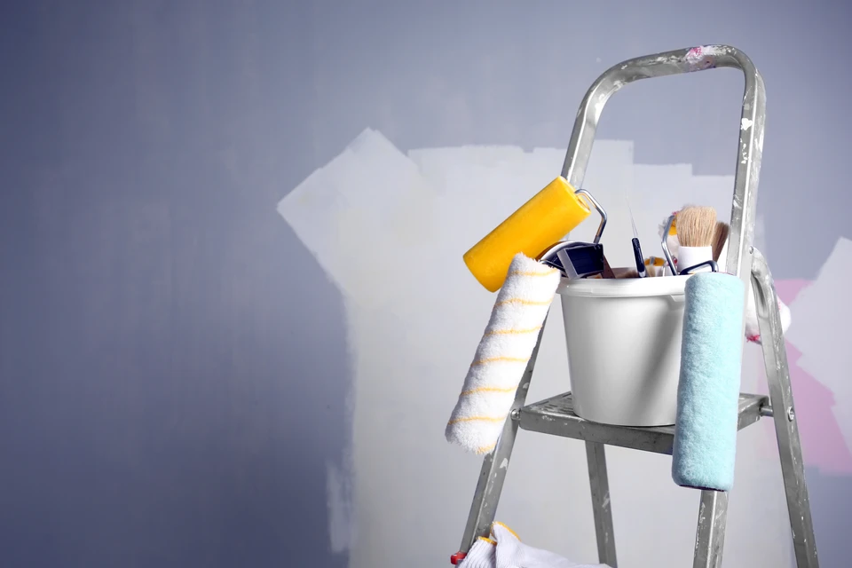 Chantier de peinture intérieure avec ouvriers en salopettes bleues et vertes appliquant de la peinture murale
